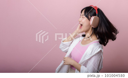 happy young asian woman model with stylish trendy sun glasses enjoy listening music by headphone audio and dancing isolated on pink studio background. technology, girl fashion, accessory concept. happy young asian woman model with stylish trendy sun glasses enjoy listening music by headphone audio and dancing isolated on pink studio background. technology, girl fashion, accessory concept. 101004580