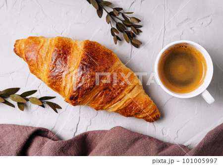 Sweet croissant with a cup of coffee and a linen towel 101005997