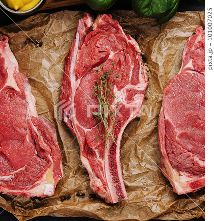 Three raw beef steaks on a wooden chopping board 101007025