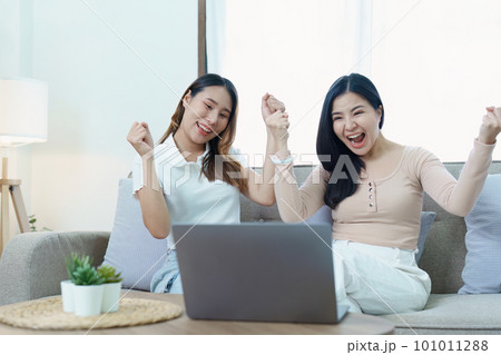 lgbtq, lgbt concept, homosexuality, portrait of two asian women posing happy together and loving each other while playing computer laptop on sofa. lgbtq, lgbt concept, homosexuality, portrait of two asian women posing happy together and loving each other while playing computer laptop on sofa. 101011288