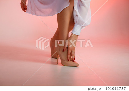 Woman's hand touches heel shoe on red background 101011787