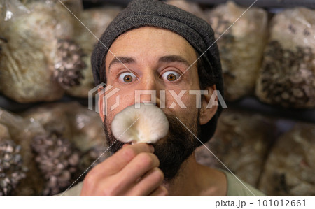 Close-up of Young cute farmer man sniffing a mushroom Close-up of Young cute farmer man sniffing a mushroom 101012661
