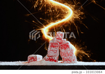 Strawberry red marmalade jelly candy's covered with powder sugar on black background with bright flash . Photo with copy space. The concept of Christmas sweets. 101013064