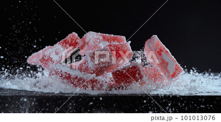 Powdered sugar is sprinkled on berry marmalade on a black background. Strawberry red marmalade jelly candy's covered with powder sugar on black background. Photo with copy space. 101013076