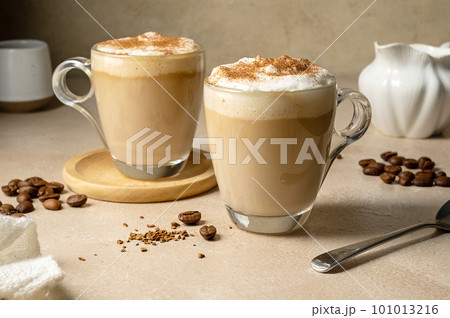 Two glass cups with coffee drink, latte with milk foam and cinnamon  101013216