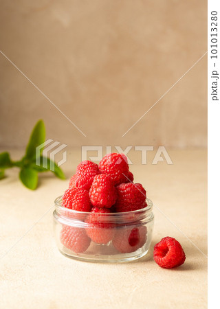 Fresh Raspberry in glass bowl, warm neutral background. 101013280