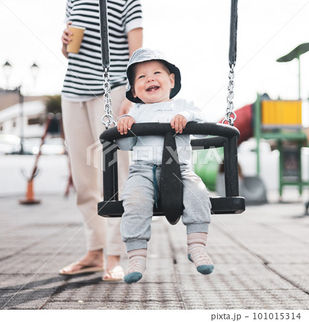Mother pushing her infant baby boy child on a swing on playground outdoors Mother pushing her infant baby boy child on a swing on playground outdoors 101015314