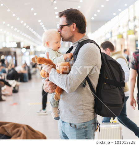 Father traveling with child, holding his infant baby boy at airport terminal waiting to board a plane. Travel with kids concept 101015329