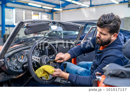 cleaning the interior of the old car with a brush and rag 101017137