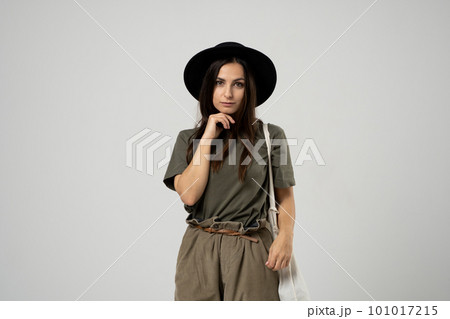 Happy smiling brunette woman in black hat with white cotton eco bag on her shoulder. Girl holding textile grocery bag with vegetables. Zero waste concept. Happy smiling brunette woman in black hat with white cotton eco bag on her shoulder. Girl holding textile grocery bag with vegetables. Zero waste concept. 101017215