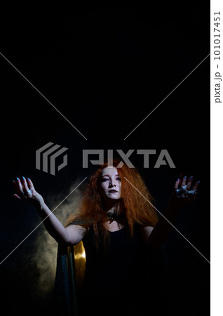 An evil red-haired witch holds fire in her hands. 101017451