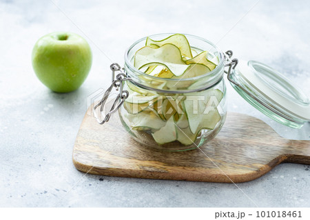 open jar with apple chips on wooden board 101018461