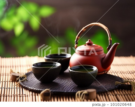 Asian tea set. Japanese teapot and cups on bamboo mat. Hot tea in pot and teacups 101020648
