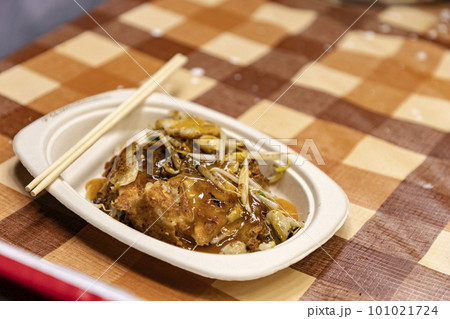 Hoy-Tod Delicious Thai food made from oysters, flour, egg and fried until crispy. Famous Thai food. Put in a disposable paper plate on a table covered with plastic checkered cloth. Selective focus. 101021724