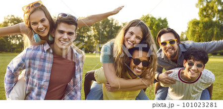 Friends who having fun, laughing and giving piggyback to each other in park on warm summer day. Friends who having fun, laughing and giving piggyback to each other in park on warm summer day. 101023281