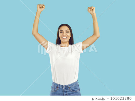 Young woman in white T shirt celebrating her victory, raising hands up and smiling Young woman in white T shirt celebrating her victory, raising hands up and smiling 101023290