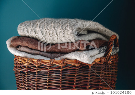Stack of knitted sweaters on wicker basket. 101024100