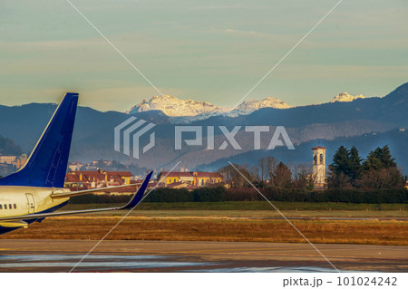 Part of airplane, suburban of Bergamo city  with church and  snowy European Alps ( Italian Alps) . View from Airport Bergamo. 101024242