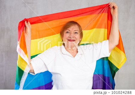 Cheerful senior woman standing confidently with rainbow flag Cheerful senior woman standing confidently with rainbow flag 101024288
