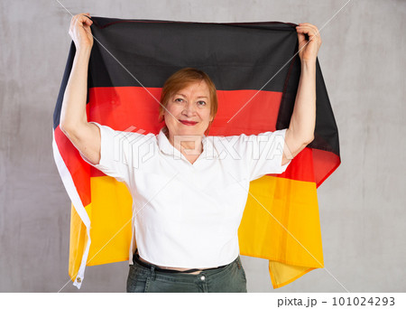 Cheerful aged woman holding national flag of Germany Cheerful aged woman holding national flag of Germany 101024293