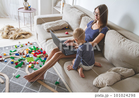 kid plays on the sofa while mom works with laptop, distracts and 101024298