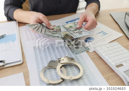 Woman counts money over table with papers and handcuffs Woman counts money over table with papers and handcuffs 101024683