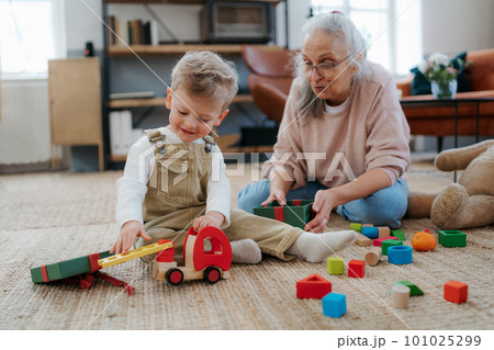 Grandmother playing with her little grandson,building a block set. Grandmother playing with her little grandson,building a block set. 101025299