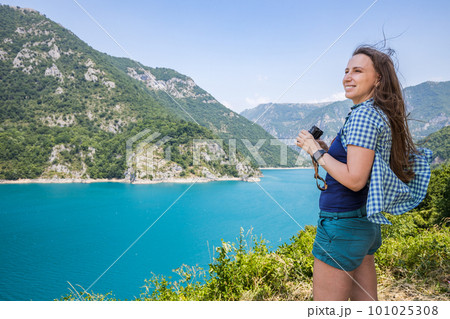 Young woman using binoculars exploring the nature at the Piva lake in Montenegro Young woman using binoculars exploring the nature at the Piva lake in Montenegro 101025308