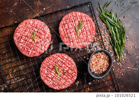 Raw burger cutlet from beef meat with spices and rosemary ready for cooking. Dark background. Top view 101026521