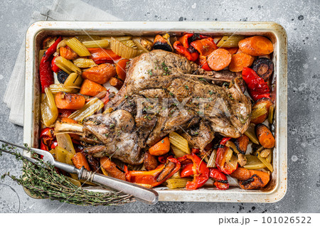 Roast lamb mutton shoulder meat in a baking dish with vegetables. Gray background. Top view 101026522