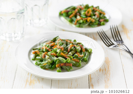 two plates with traditional green bean casserole sprinkled with crispy fried onions  on a white wooden table. 101026612