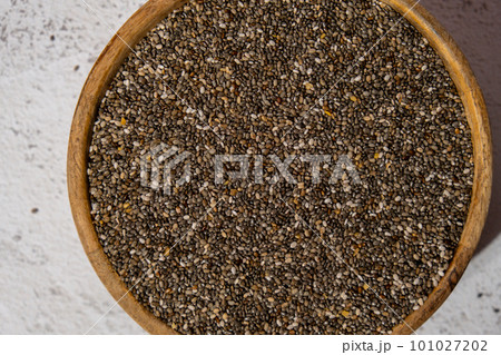 Chia seeds in wooden bowl. Healthy superfood rich in Omega 3 fatty acids. Dry healthy natural ingredient. Chia grains are falling Chia seeds in wooden bowl. Healthy superfood rich in Omega 3 fatty acids. Dry healthy natural ingredient. Chia grains are falling 101027202