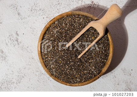 Chia seeds in wooden bowl with wooden spoon. Healthy superfood rich in Omega 3 fatty acids. Dry healthy natural ingredient. Chia grains are falling Chia seeds in wooden bowl with wooden spoon. Healthy superfood rich in Omega 3 fatty acids. Dry healthy natural ingredient. Chia grains are falling 101027203