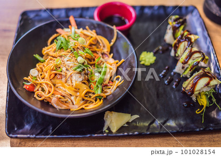 Asian noodles and sushi in black bowl Asian noodles and sushi in black bowl 101028154