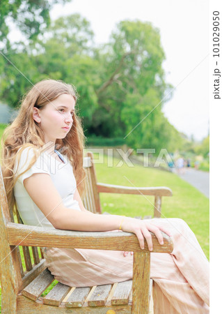 公園のベンチに座る外国人少女の横顔（縦写真） 101029050