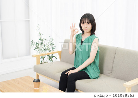 ソファーに座ってOKサインをする若い女性 101029562