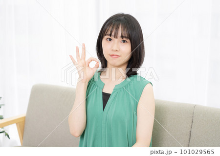 ソファーに座ってOKサインをする若い女性 ソファーに座ってOKサインをする若い女性 101029565