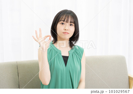 ソファーに座ってOKサインをする若い女性 101029567