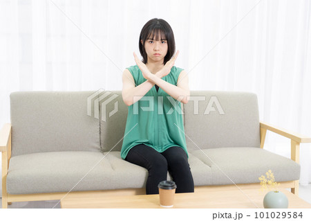ソファに座ってNGのサインをする若い女性 ソファに座ってNGのサインをする若い女性 101029584