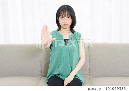 ソファに座ってNGのサインをする若い女性 ソファに座ってNGのサインをする若い女性 101029586