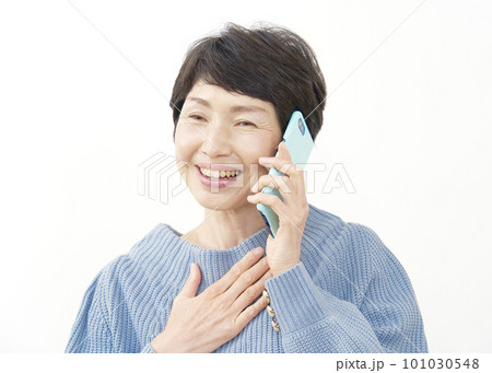 胸を撫で下ろすしてスマホで電話する中年女性　白背景 101030548