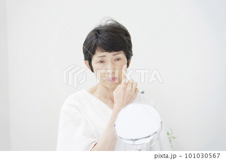 鏡で顔を見て悩んでいる中年女性 101030567