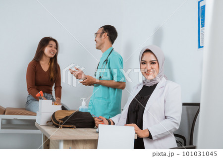 a female doctor in doctor's coat sitting on her desk a female doctor in doctor's coat sitting on her desk 101031045