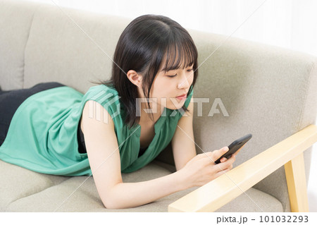 ソファに寝転んでスマホを使う若い女性 ソファに寝転んでスマホを使う若い女性 101032293