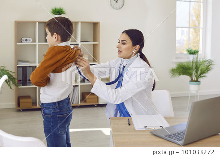 Boy in clinic for a checkup. Doctor with stethoscope examining child's lungs and heartbeat. 101033272