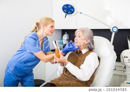 Senior woman and cosmetologist looking in mirror 101034585