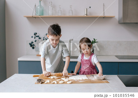 Siblings making cookies, preparing Easter. 101035546