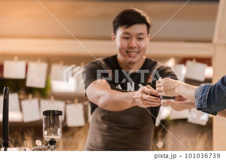 Asian man, coffee maker, handing over a cup of coffee Served to female customers counter, Startup Business Concept. Asian man, coffee maker, handing over a cup of coffee Served to female customers counter, Startup Business Concept. 101036739