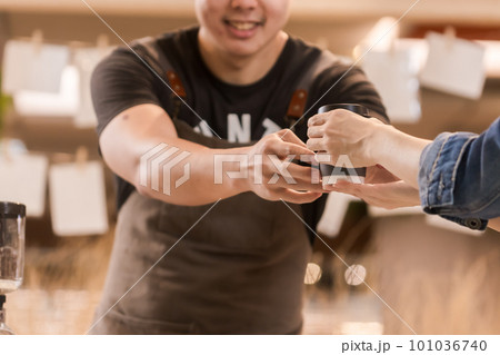 Asian man, coffee maker, handing over a cup of coffee Served to female customers counter, Startup Business Concept. Asian man, coffee maker, handing over a cup of coffee Served to female customers counter, Startup Business Concept. 101036740