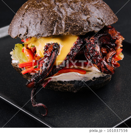 Appetizing marinated octopus burger on a black tray Appetizing marinated octopus burger on a black tray 101037556